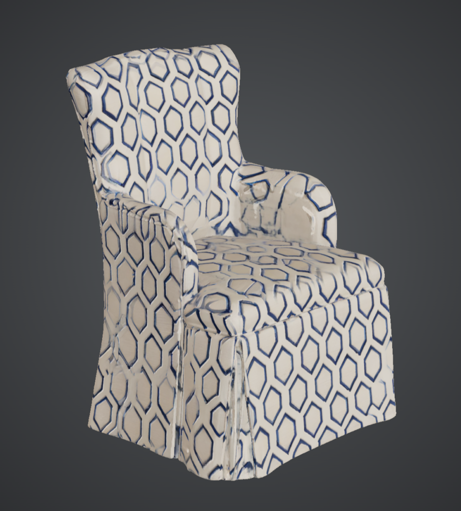 An upholstered armchair with a slipcovered silhouette, covered in a cream fabric printed with blue geometric links. Its tall back, padded arms, and skirted base are shown in three-quarter view against a plain dark gray backdrop, with soft studio lighting emphasizing the fabric's pattern and folds. Home Design, Rendering, Annilee Waterman, Dallas Texas