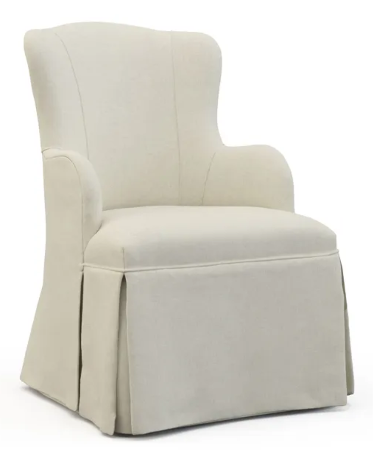 An upholstered ivory wingback chair with rounded arms and a tailored skirt, its smooth fabric softly wrapping the high back and cushioned seat. Centered against a clean white background, the piece is evenly lit, giving its neutral tones a calm, refined presence. Home Design, Rendering, Annilee Waterman, Dallas Texas