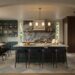 A spacious modern kitchen and dining area features a large central island with four dark upholstered stools, teal cabinetry, and a marble backsplash with veined stone. A wooden dining table, brass chandelier, and tall windows frame the room, while warm wood cabinetry and soft daylight create a refined, layered interior. Home Design, Rendering, Annilee Waterman, Dallas Texas